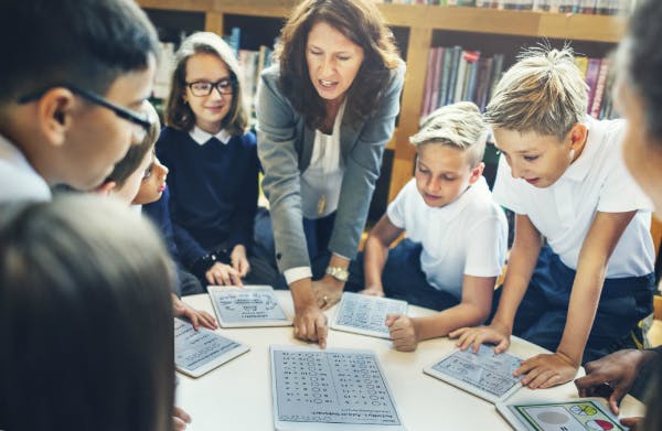 Teacher leading a group of students in a classroom activity.
